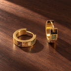 Gold plated titanium alloy huggie earrings with square natural stone inlays on dark wood