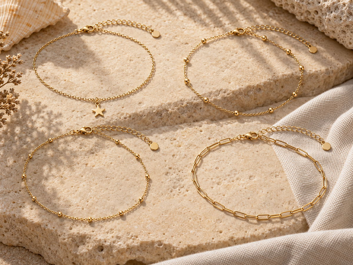 Gold plated chain anklets with star charms and bead details on warm limestone