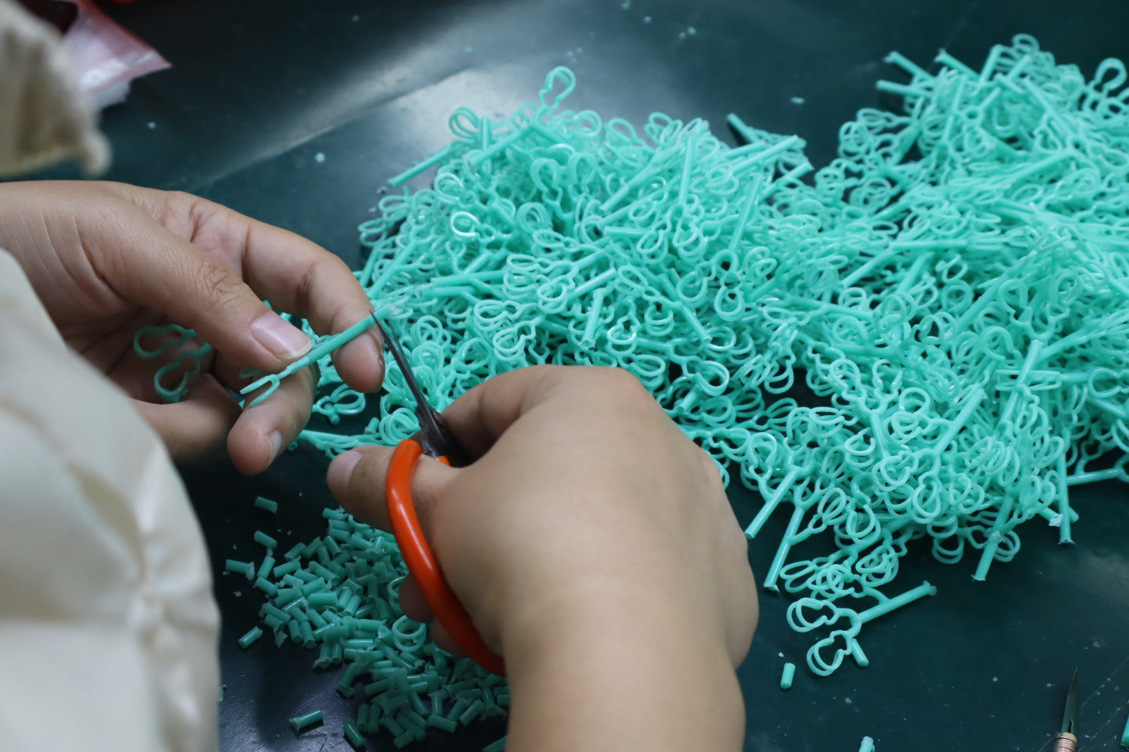 Hands trimming turquoise wax jewelry models before casting